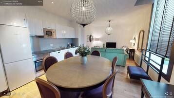 A modern kitchen with white cabinets, a Bosch microwave, and a chandelier.