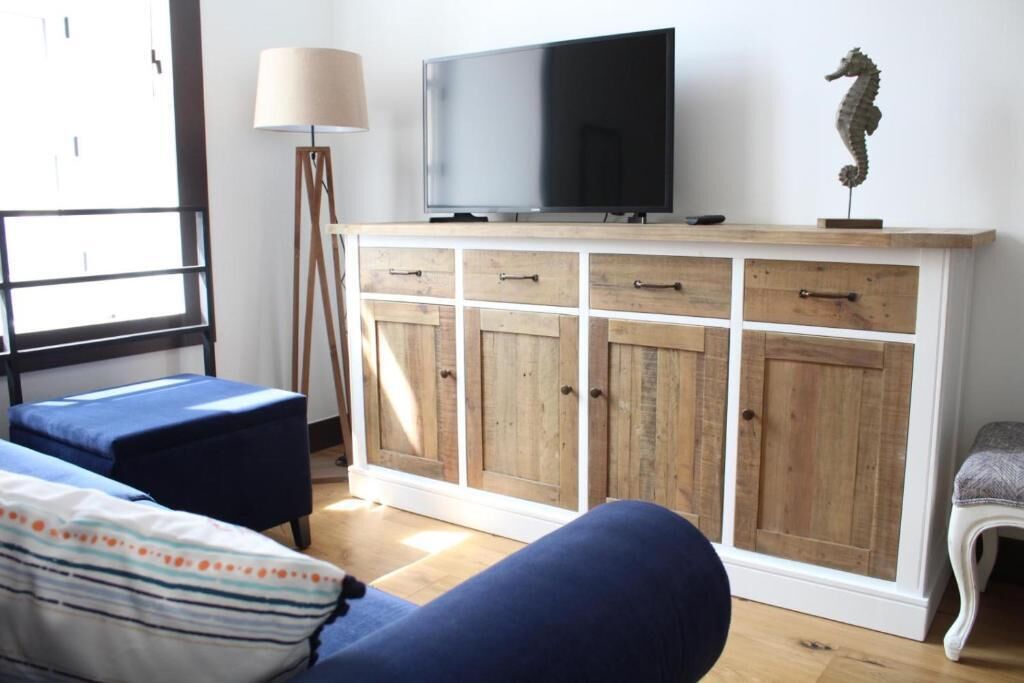 Una sala de estar con un aparador de madera, un televisor y una decoración con caballito de mar.