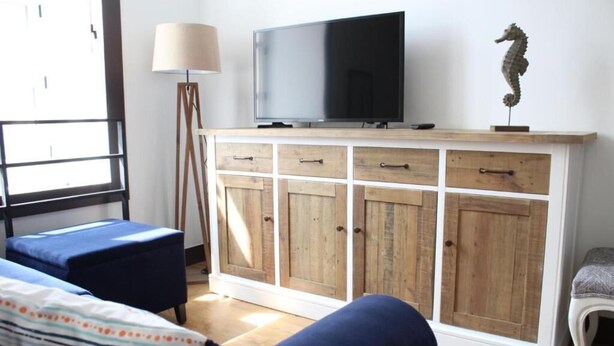Una sala de estar con un aparador de madera, un televisor y una decoración con caballito de mar.