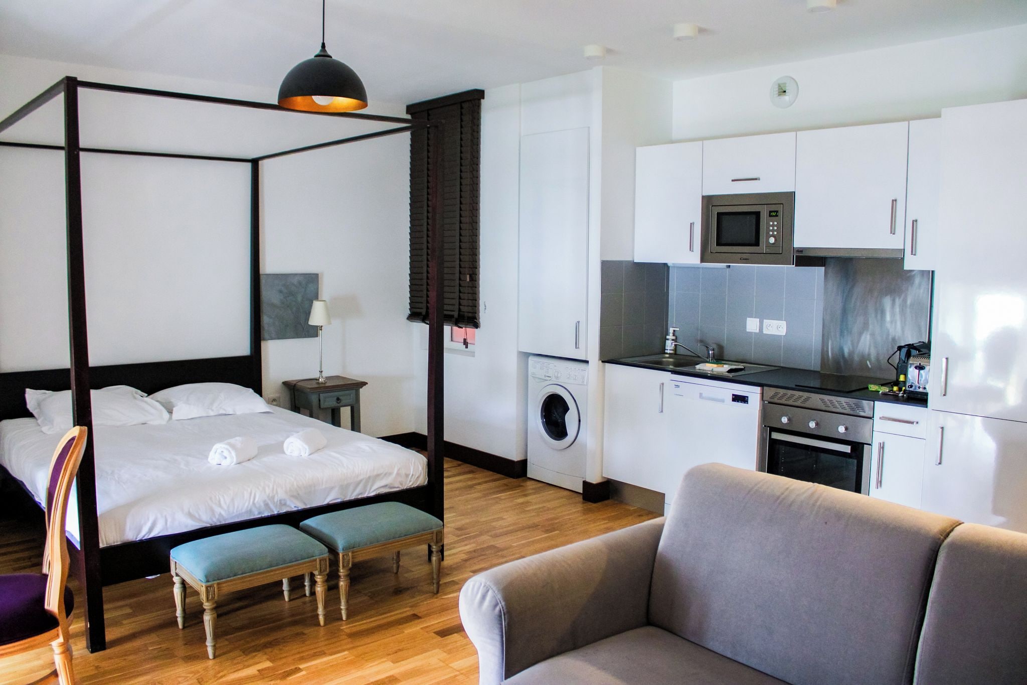 Ein Schlafzimmer mit Himmelbett, Waschmaschine, Mikrowelle und einer Küchenzeile.