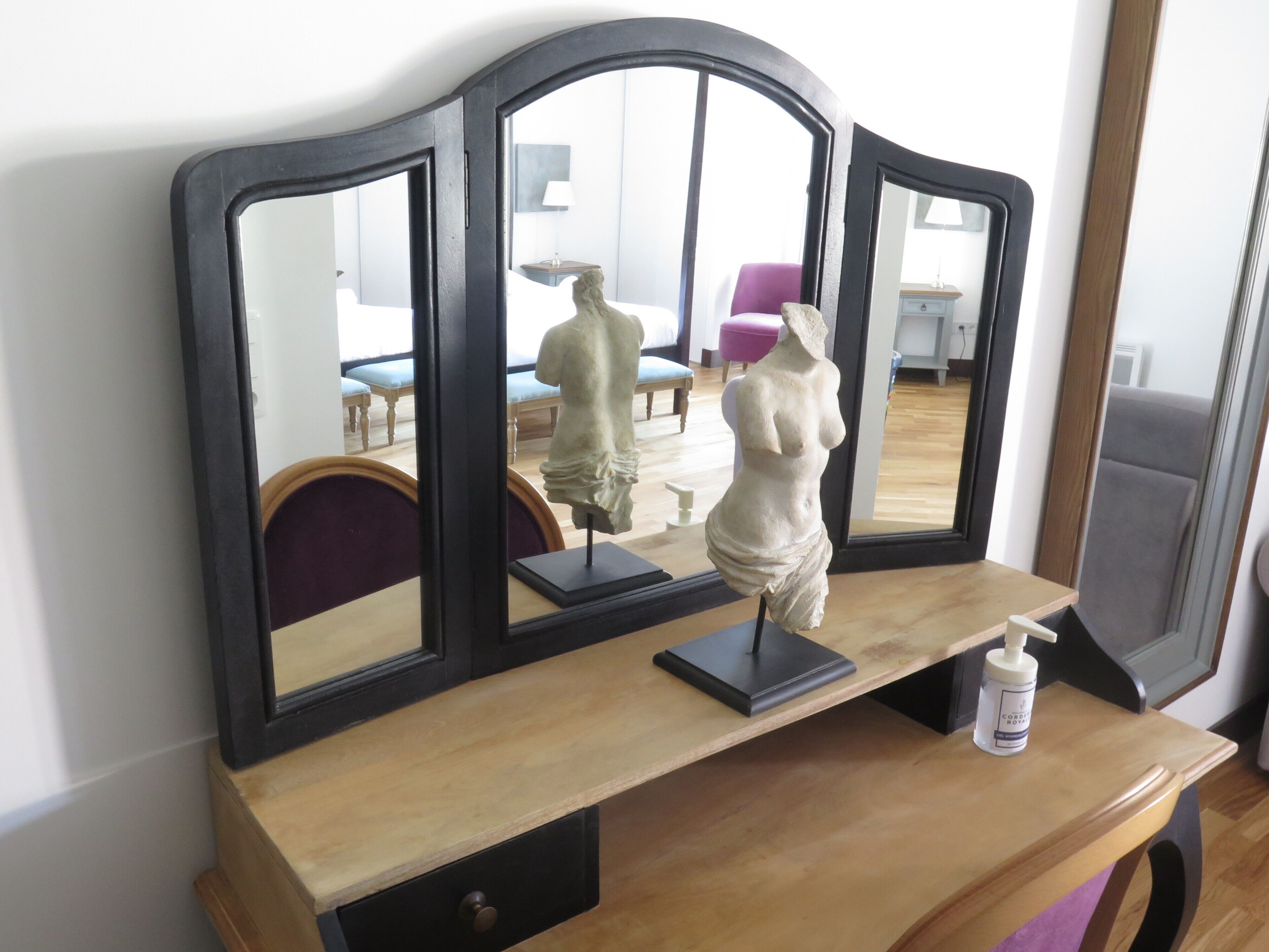 A wooden vanity with a mirror and a statue.