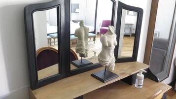 A wooden vanity with a mirror and a statue.