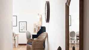 Una escalera conduce a un comedor con mobiliario de mimbre y un espejo.