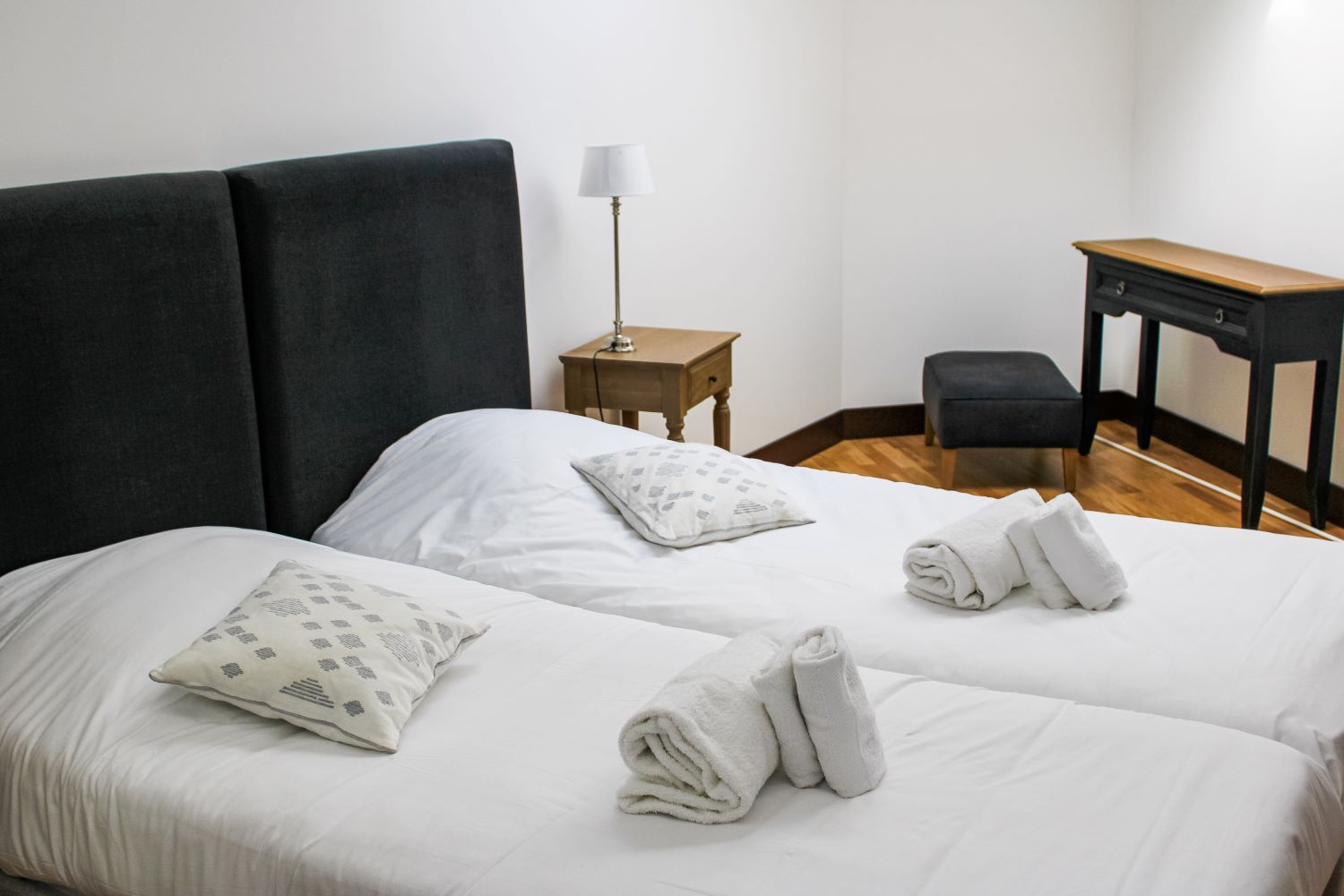 Ein Hotelzimmer mit zwei Betten, einem Schreibtisch, einem Stuhl und einer Lampe.