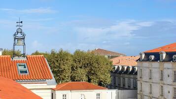 A courtyard with red-tiled roofs, a bell tower, and a building with a white facade.