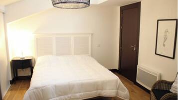 A bedroom with a bed, a nightstand, a door, and a radiator.