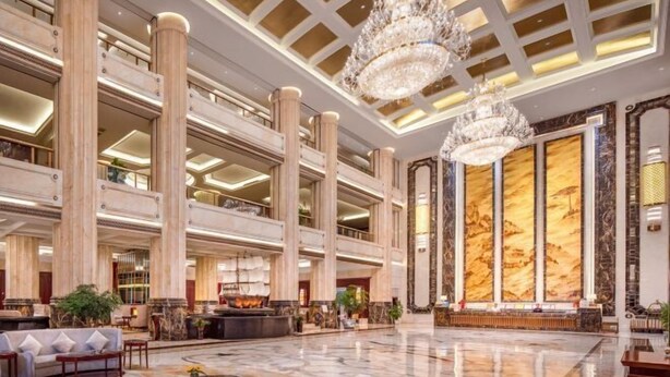 A spacious lobby with high ceilings, marble columns, and a grand chandelier. - Hui En International Hotel (Gao'an)
