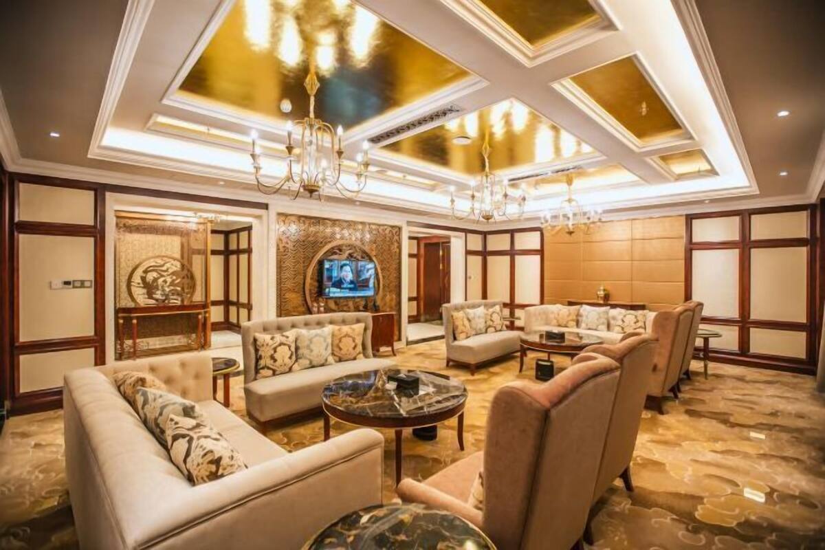 Un amplio salón con varios sofás y sillones, un televisor y una araña.