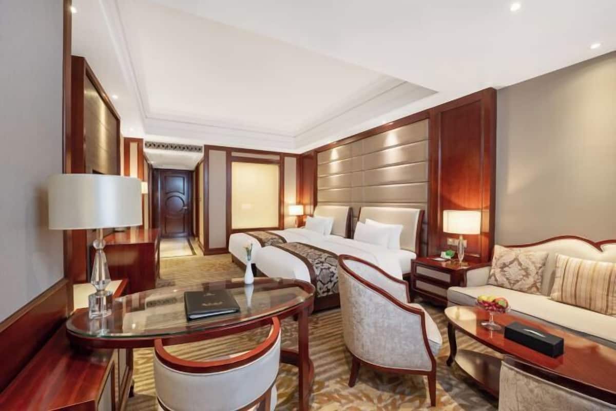 Habitación de hotel con cama, zona de estar con mesa y sillas, escritorio y sofá.