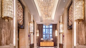 A grand hallway with a marble floor, ornate chandeliers, and a large window with curtains. - Hui En International Hotel (Gao'an)