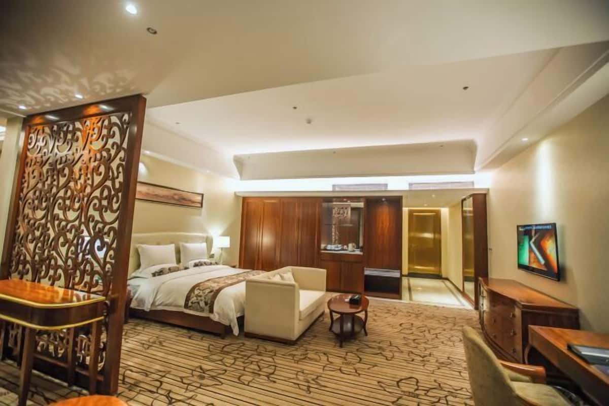 Una habitación de hotel con cama, sofá, escritorio y televisor.