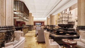A spacious lobby with marble columns, plush seating, a grand staircase, and a large ship model display. - Hui En International Hotel (Gao'an)