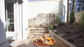 A balcony with a table set for breakfast, including bread, fruit, and juice. - Lyonest Chambre D'hôtes (Lyon)