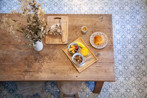 A wooden table with a fruit bowl, a plate of food, a vase with dried flowers, and a cutting board with a knife. - Lyonest Chambre D'hôtes (Lyon)