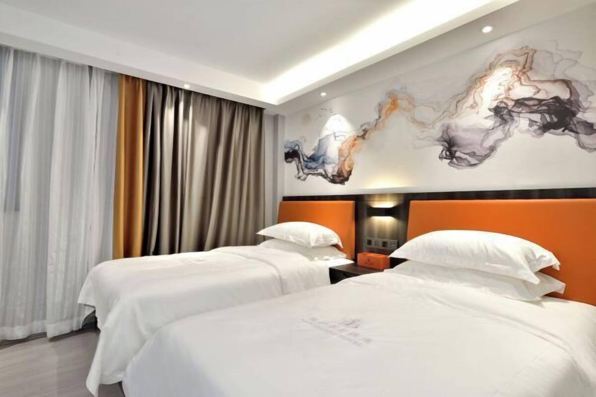 A hotel room with two beds, a modern wall art piece, and a large window with curtains.