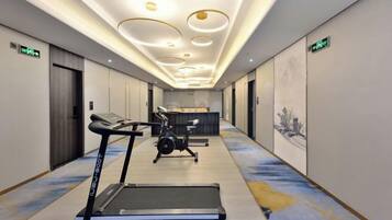 A hotel corridor with exercise equipment, including treadmills and a stationary bike, and a reception desk.