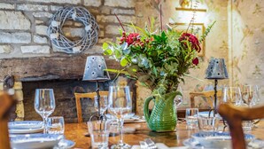 A dining table set with plates, glasses, and cutlery, surrounded by chairs. - Characterful holiday cottage in the heart of Bourton-on-the-Water - Pear Tree Cottage, Bourton (Cheltenham)