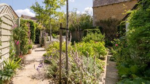 A narrow garden path leading to a house with a stone facade and a tiled roof. - Characterful holiday cottage in the heart of Bourton-on-the-Water - Pear Tree Cottage, Bourton (Cheltenham)
