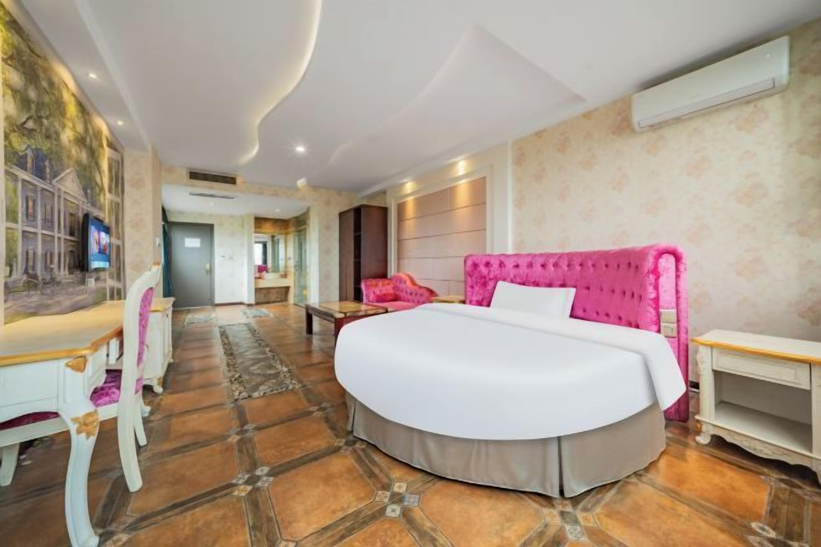 A spacious bedroom with a large bed, a desk, and a chair.