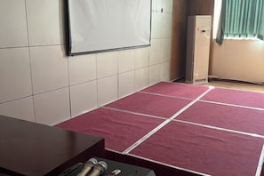 Une pièce dont le sol est recouvert d’une moquette rouge, avec un tableau blanc au mur et un meuble.