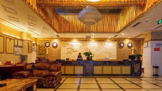 A lobby with a reception desk, a chandelier, a clock, and a seating area with a couch and a table. - Hotel Schönbrunn Palace (Chongqing)