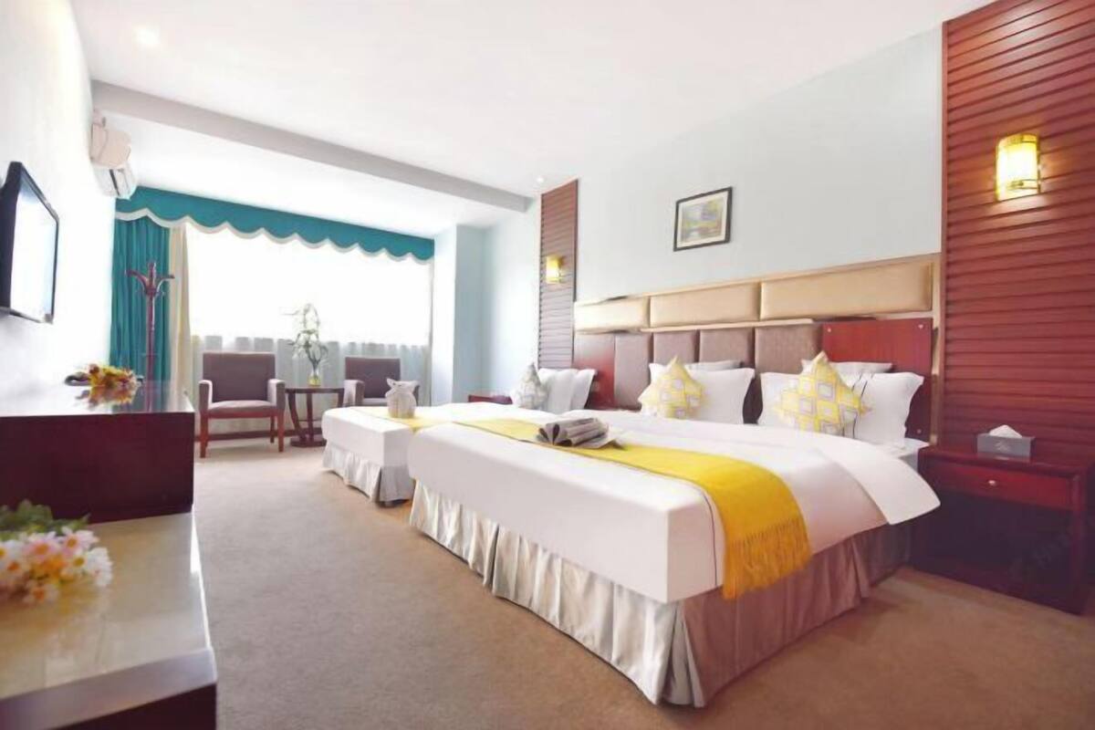 Une chambre d’hôtel avec un grand lit, un bureau et une chaise. Il y a une fenêtre donnant sur l’extérieur.