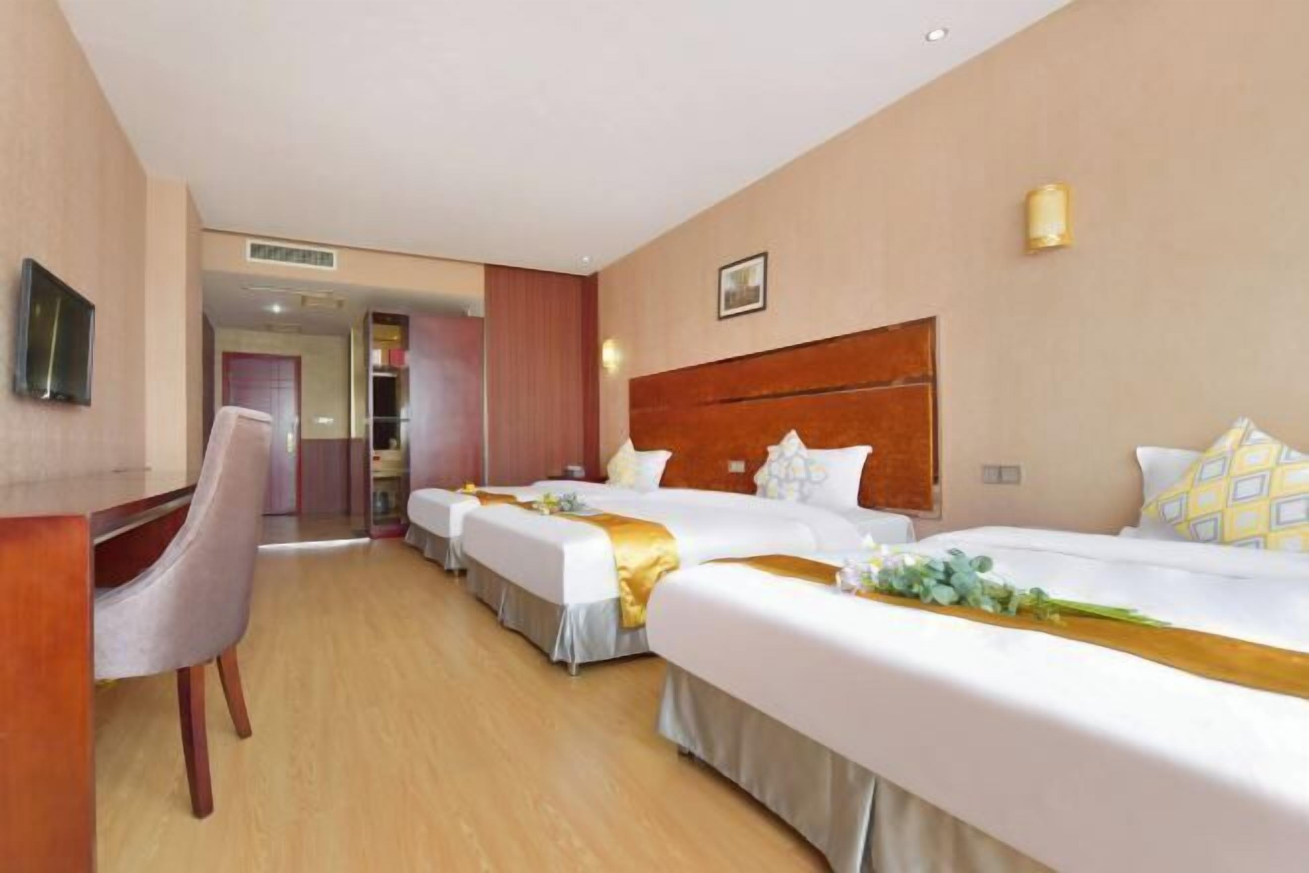 A hotel room with two beds, a desk, and a chair.
