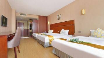 A hotel room with two beds, a desk, and a chair.