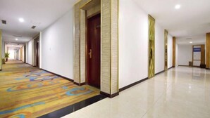 A long, narrow hallway with a patterned carpet and a tiled floor. - Hotel Schönbrunn Palace (Chongqing)