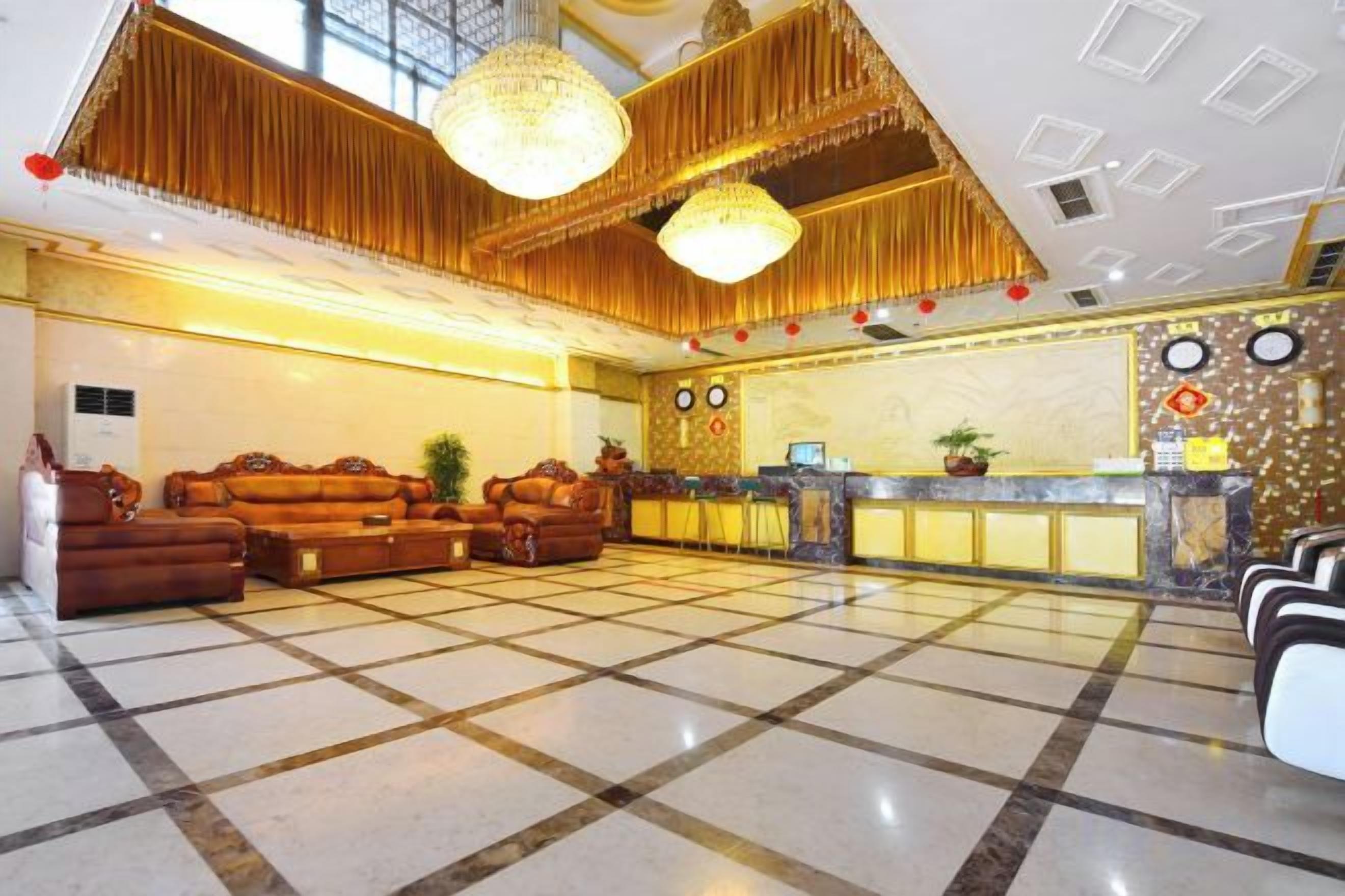 A hotel lobby with a check-in counter, seating area, and a chandelier.