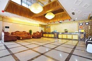 Una hall d'albergo con reception, zona relax e lampadario.