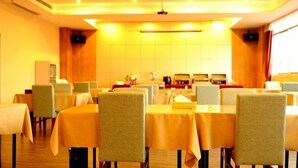 A dining area with tables and chairs, a kitchen in the background, and a warm yellow lighting. - Hotel Schönbrunn Palace (Chongqing)
