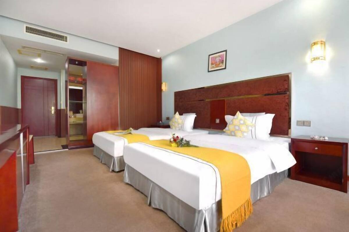 Une chambre d’hôtel avec deux lits, une tête de lit en bois, une table de chevet et une armoire.