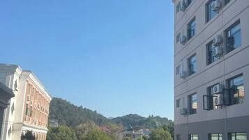 A multi-story building with a clear sky and a hilly landscape in the background.