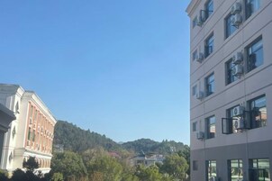 Un edificio de varios pisos con cielo despejado y un paisaje montañoso al fondo.