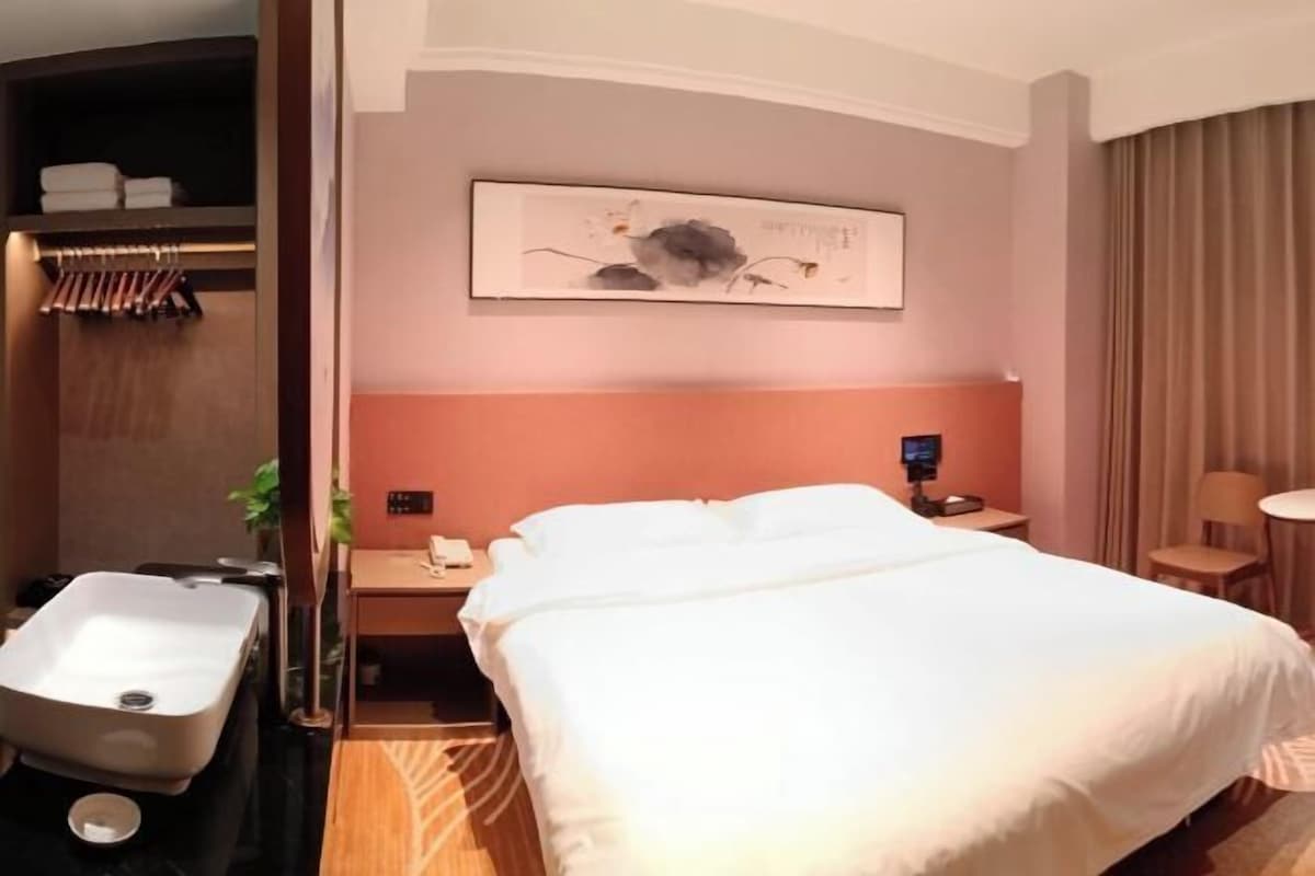 Hotellihuone, jossa on sänky, yöpöytä, työpöytä, tuoli, kylpyhuone, jossa on pesuallas, ja pyyheteline.