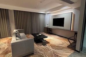 Una sala de estar moderna con un sofá, una mesa de centro y un televisor de pantalla plana grande montado en la pared.