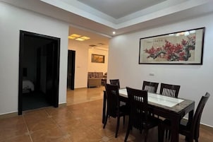 Un comedor con una mesa y sillas, una obra de arte enmarcada en la pared, y una puerta que da a otra habitación.