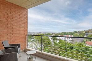 A balcony with wicker furniture and a small table, overlooking a cityscape with greenery and buildings. - 601 at Two six two Florida Road (Durban)