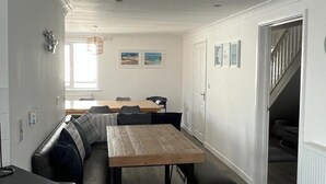 A compact kitchen with a wooden table, bench seating, and a view of the adjacent living area. - Bescot House, Bramble Hill, Bude, 4 bed det House (Bude)