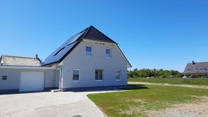 A modern two-story house with a sloped roof, a garage, and a paved driveway. - New, exclusive vacation home close to the beach with sauna, 3 bedrooms, fireplace, WLAN, garage (Dranske-Lancken)