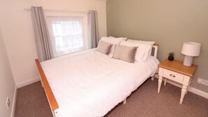 A neatly arranged bedroom with a bed, bedside table, lamp, and a window with curtains. - Beautiful 2 bed Cottage in the Centre of Richmond (Richmond)