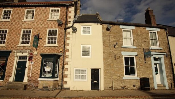 A row of traditional brick buildings with multiple windows and doors, some with signs above them. - Beautiful 2 bed Cottage in the Centre of Richmond (Richmond)