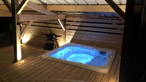 A hot tub in a wooden deck area with a covered roof structure. - Chalet du Fayard in Belfahy, private Jacuzzi and view of the Vosges mountains (Belfahy)