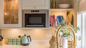 A kitchen with a microwave, tea kettle, and storage jars labeled coffee, sugar, and tea.