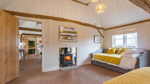 A cozy bedroom with a wooden floor, a bed with yellow bedding, a fireplace, and a large mirror on the wall.