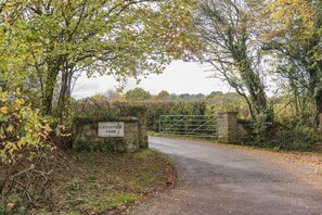Entrada a una granja rural con una puerta de piedra y un letrero que dice 'Lodgefield Farm'.