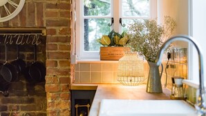A kitchen with a brick wall, hanging pots, a window with a view of trees, a wooden box labeled "HOME GROWN", and a vase with flowers. - Wow, wow! Amazing immaculate period house and hot tub by Bloom Stays - discounts available (Faversham)