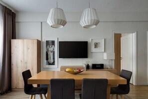 Un espace repas moderne avec une table en bois, des chaises noires et un saladier rempli de fruits.