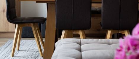 A modern dining area with a wooden table, black chairs, and a flat-screen TV mounted on the wall.